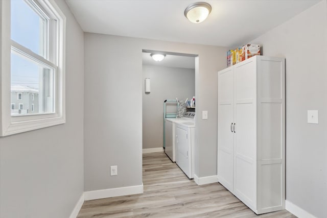 laundry room with washing machine and dryer, light wood-type flooring, and a wealth of natural light