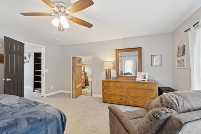 bedroom with light carpet, ensuite bathroom, a walk in closet, ceiling fan, and a closet