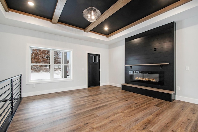 unfurnished living room featuring a fireplace, wood-type flooring, a chandelier, and beam ceiling