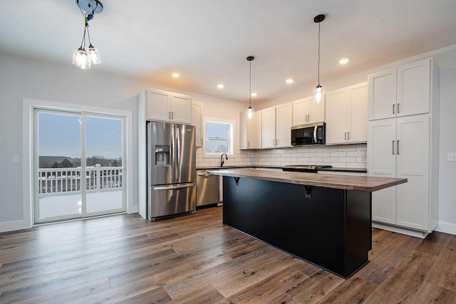 kitchen featuring white cabinetry, a healthy amount of sunlight, a kitchen island, and stainless steel appliances