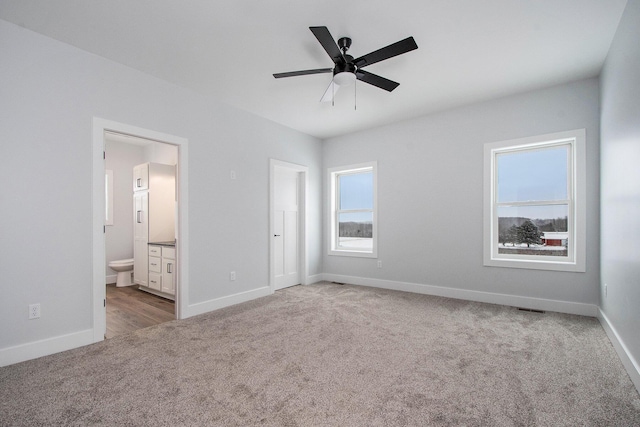 unfurnished bedroom with carpet, ensuite bathroom, and ceiling fan