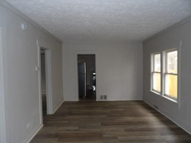 spare room featuring dark hardwood / wood-style flooring and a textured ceiling