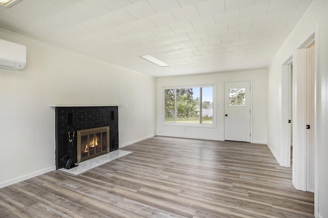 unfurnished living room with a wall mounted air conditioner, light hardwood / wood-style floors, ornamental molding, and a brick fireplace