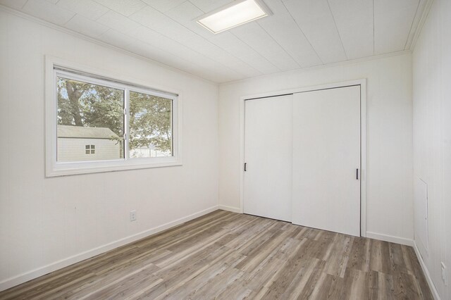 unfurnished bedroom featuring a closet, light hardwood / wood-style flooring, and crown molding