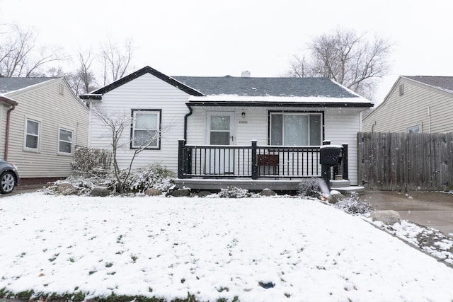 snow covered rear of property with a porch