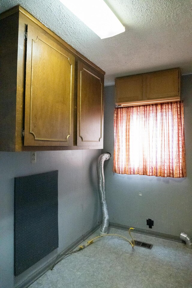 clothes washing area with a textured ceiling