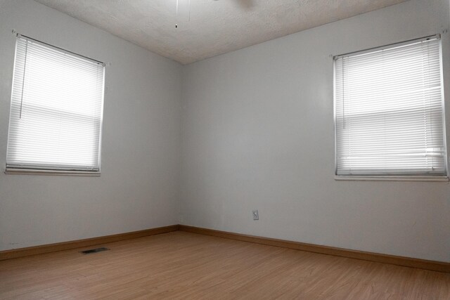 empty room featuring a textured ceiling and light hardwood / wood-style flooring