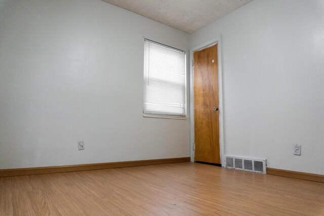 spare room featuring light hardwood / wood-style floors and a textured ceiling