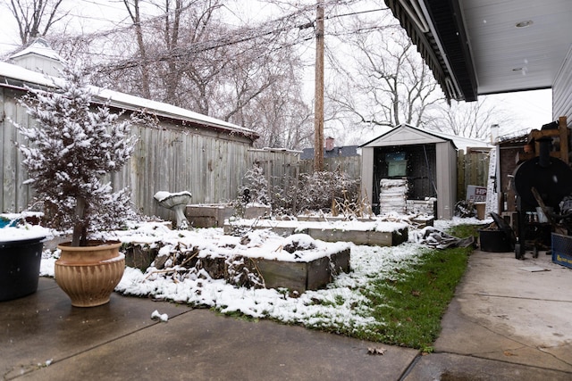 snow covered patio featuring a storage shed