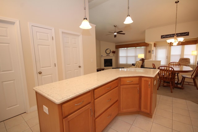 kitchen with pendant lighting, ceiling fan with notable chandelier, a center island, and light tile patterned floors