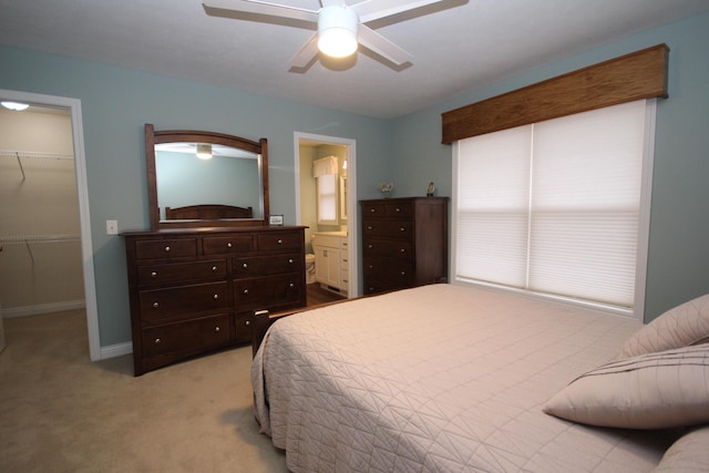 bedroom with a walk in closet, light colored carpet, ceiling fan, connected bathroom, and a closet