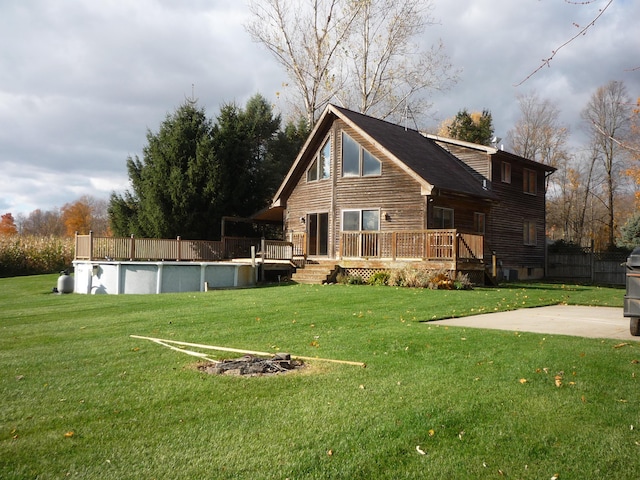 back of house with a swimming pool side deck and a yard