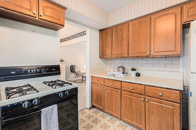 kitchen with refrigerator, white gas range oven, and tasteful backsplash