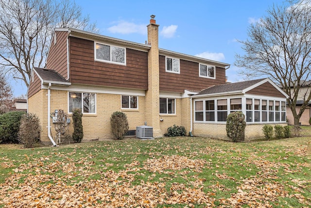 rear view of house with a sunroom, a yard, and central AC