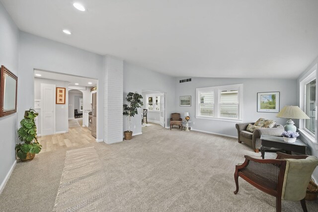 living area featuring light colored carpet and vaulted ceiling