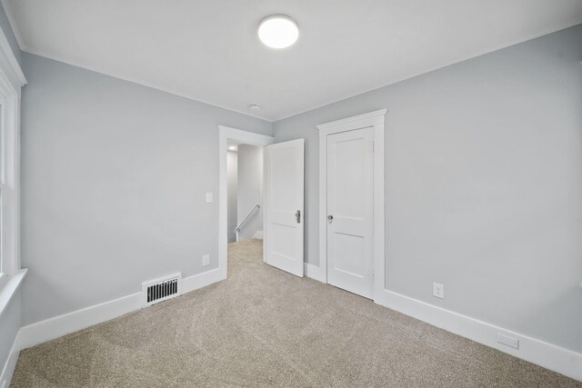 unfurnished bedroom featuring light carpet and a closet