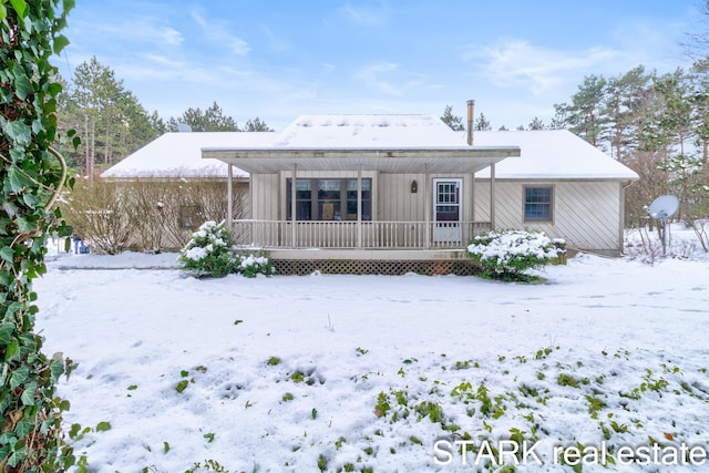 snow covered rear of property with a porch