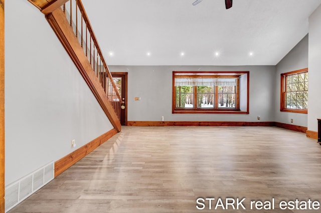 unfurnished living room featuring ceiling fan, plenty of natural light, lofted ceiling, and light wood-type flooring