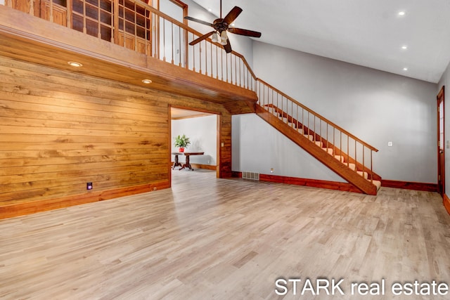 unfurnished living room with a high ceiling, light hardwood / wood-style flooring, and ceiling fan