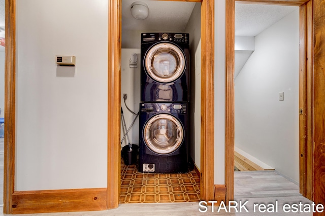 laundry area with stacked washer and dryer and a textured ceiling