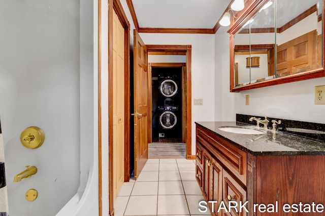 bathroom with vanity, stacked washing maching and dryer, tile patterned floors, and crown molding