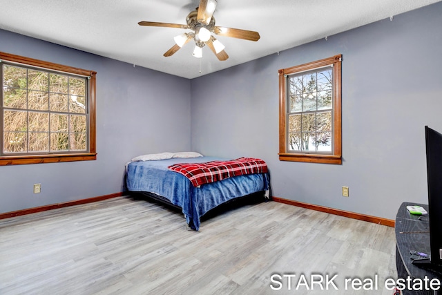 bedroom with multiple windows, ceiling fan, light hardwood / wood-style flooring, and a textured ceiling