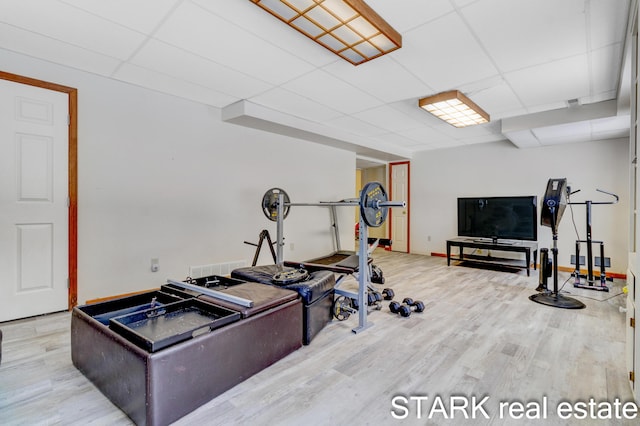 exercise room with a paneled ceiling and light wood-type flooring