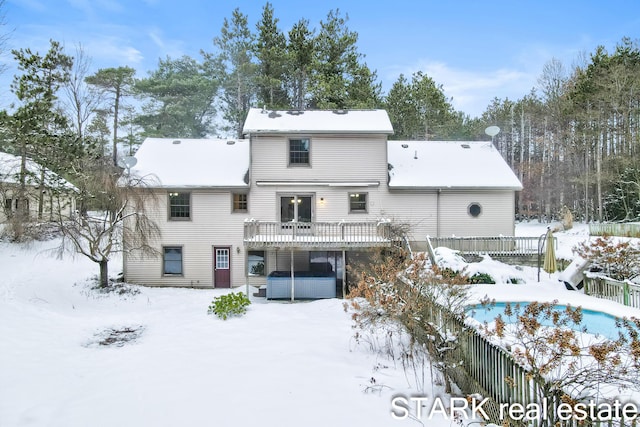 snow covered property featuring a jacuzzi and a wooden deck