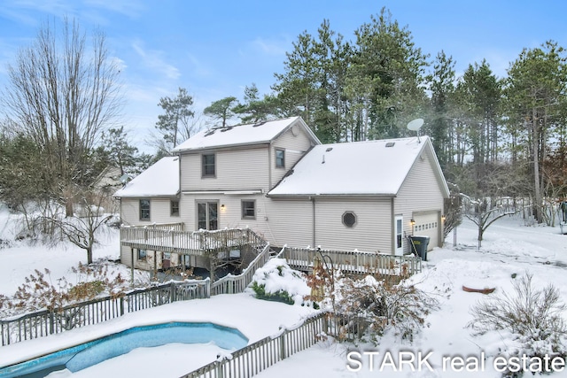 snow covered property with a deck and a garage