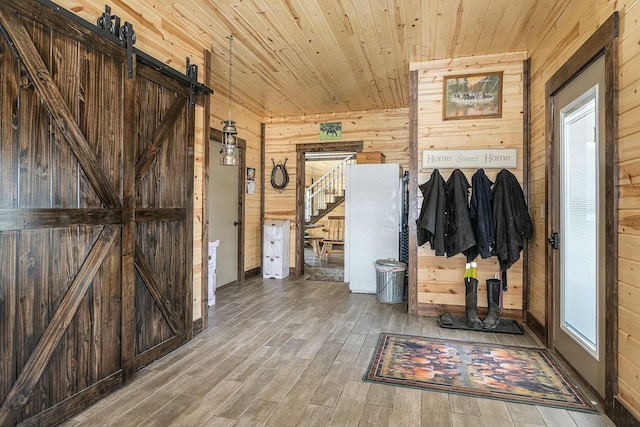 mudroom featuring a barn door, wood walls, wood ceiling, and hardwood / wood-style flooring