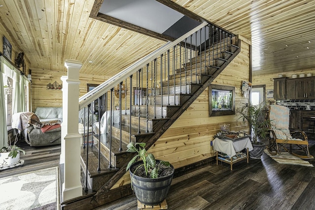 staircase with ornate columns, wooden ceiling, hardwood / wood-style floors, a towering ceiling, and wooden walls