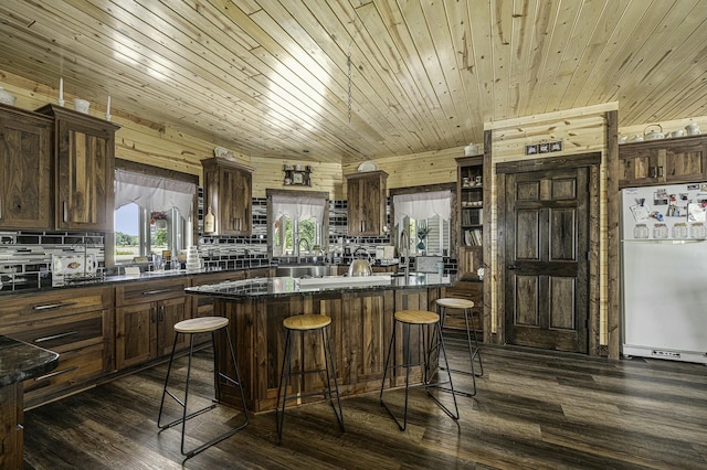 kitchen with a breakfast bar, white fridge, wooden ceiling, and wood walls