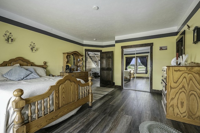 bedroom featuring a textured ceiling, dark wood-type flooring, and access to outside