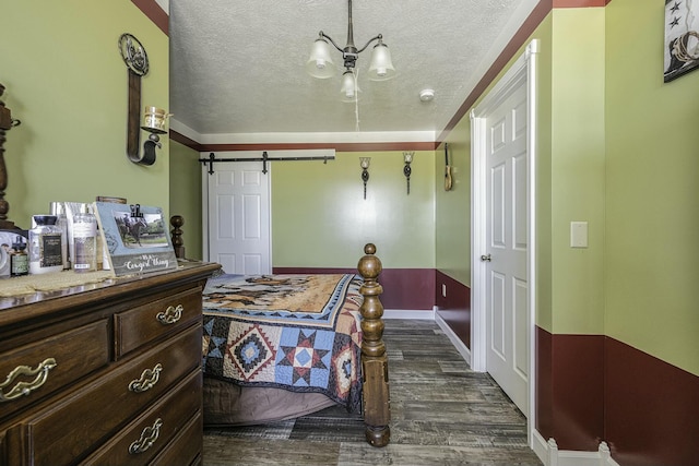 bedroom featuring a barn door, dark hardwood / wood-style flooring, a textured ceiling, and a notable chandelier