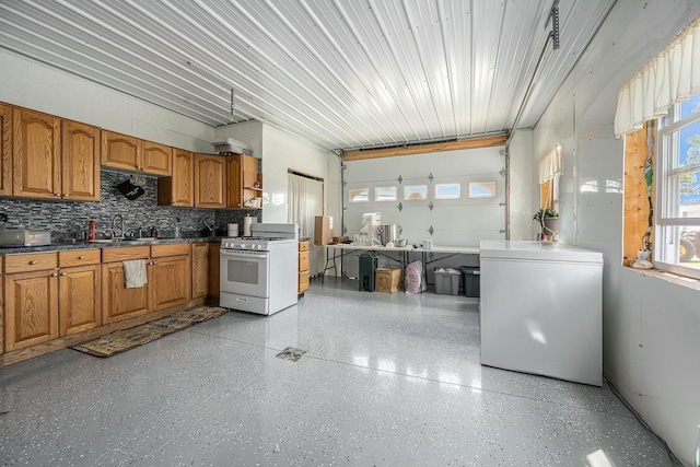 kitchen featuring white range with gas cooktop, decorative backsplash, sink, and refrigerator