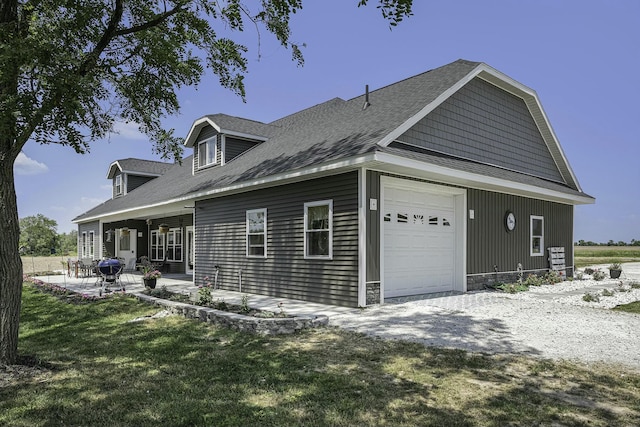 view of side of property with a porch, a garage, and a lawn