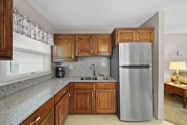 kitchen featuring a textured ceiling, stainless steel fridge, sink, and tasteful backsplash