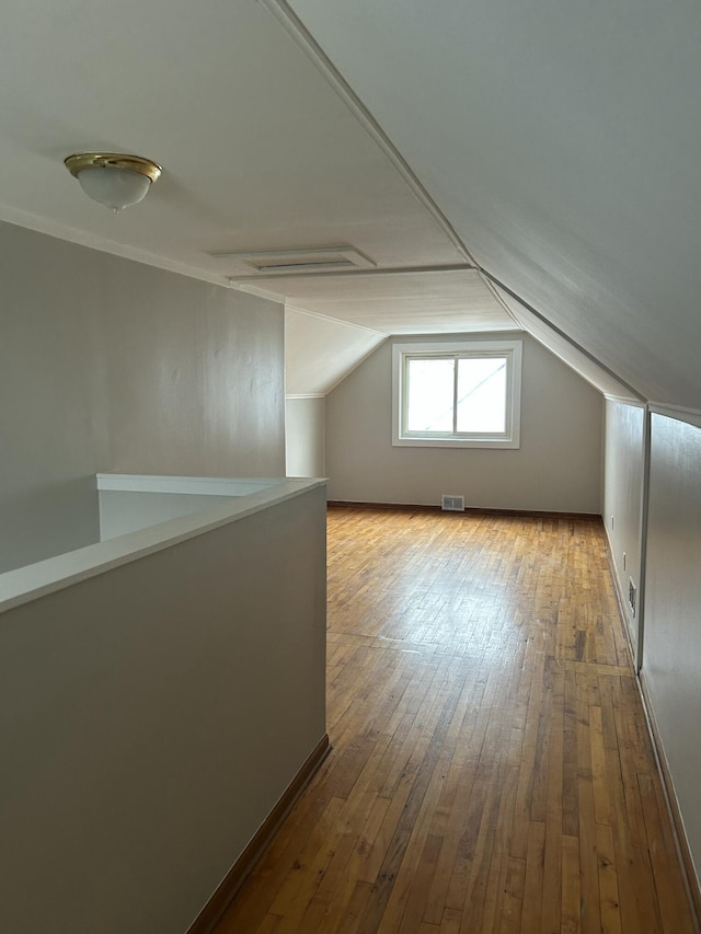 additional living space with hardwood / wood-style flooring and lofted ceiling