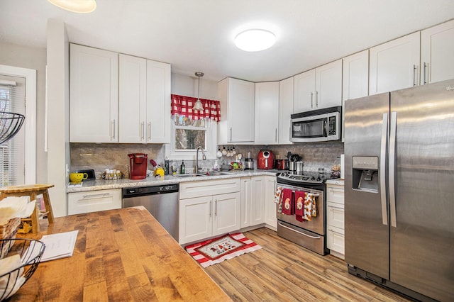 kitchen with wooden counters, white cabinets, sink, light hardwood / wood-style flooring, and stainless steel appliances