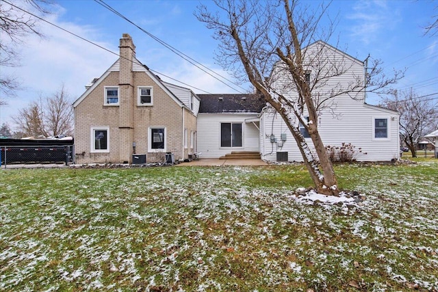 snow covered rear of property with a yard, a patio, and central AC