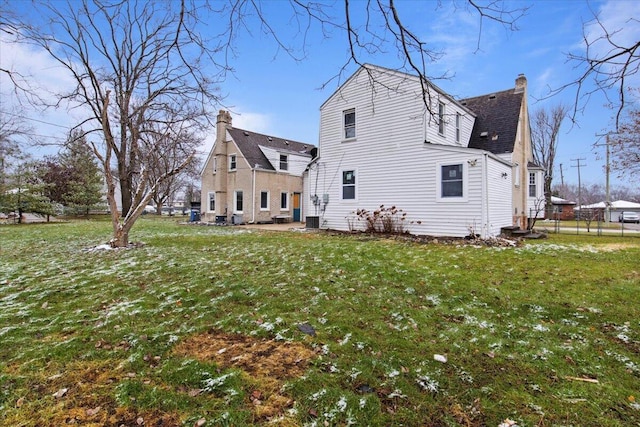 back of property featuring central air condition unit and a lawn