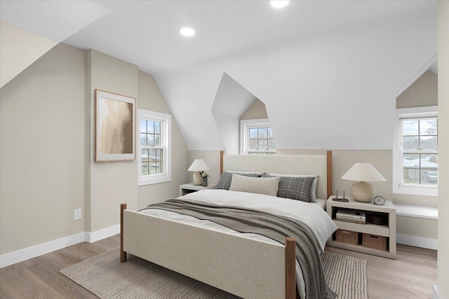 bedroom with lofted ceiling, multiple windows, and light hardwood / wood-style flooring