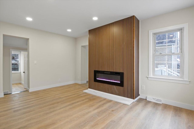 unfurnished living room featuring a large fireplace and light hardwood / wood-style floors