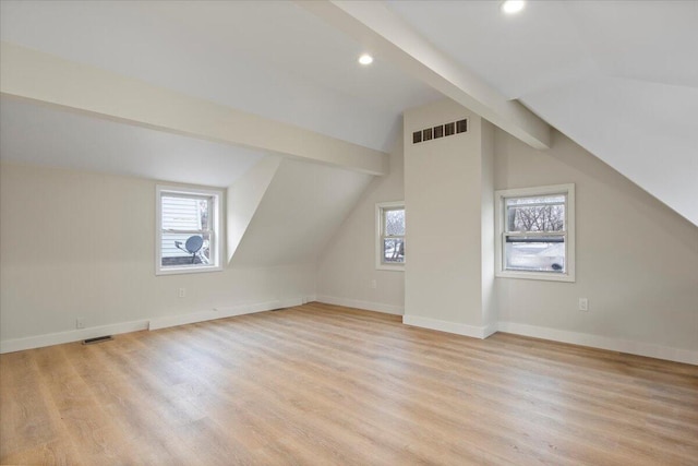 additional living space with vaulted ceiling with beams and light wood-type flooring