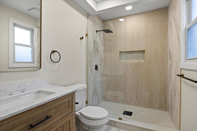 bathroom featuring vanity, toilet, and tiled shower