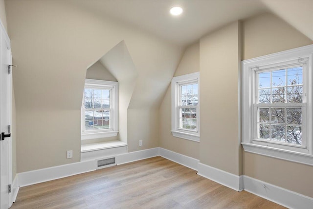 additional living space with light hardwood / wood-style floors and vaulted ceiling