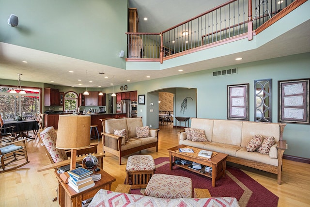 living room featuring light wood-type flooring and a towering ceiling