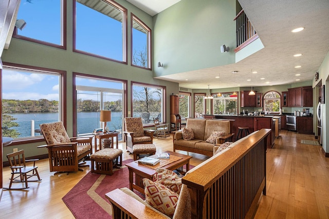 living room featuring a water view, a wealth of natural light, and light hardwood / wood-style flooring