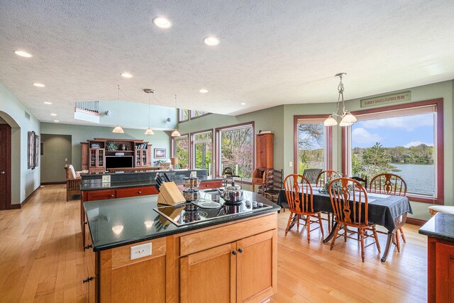 kitchen with a textured ceiling, black electric cooktop, decorative light fixtures, light hardwood / wood-style flooring, and a kitchen island