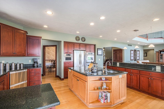 kitchen featuring a kitchen island with sink, hanging light fixtures, sink, light hardwood / wood-style flooring, and appliances with stainless steel finishes